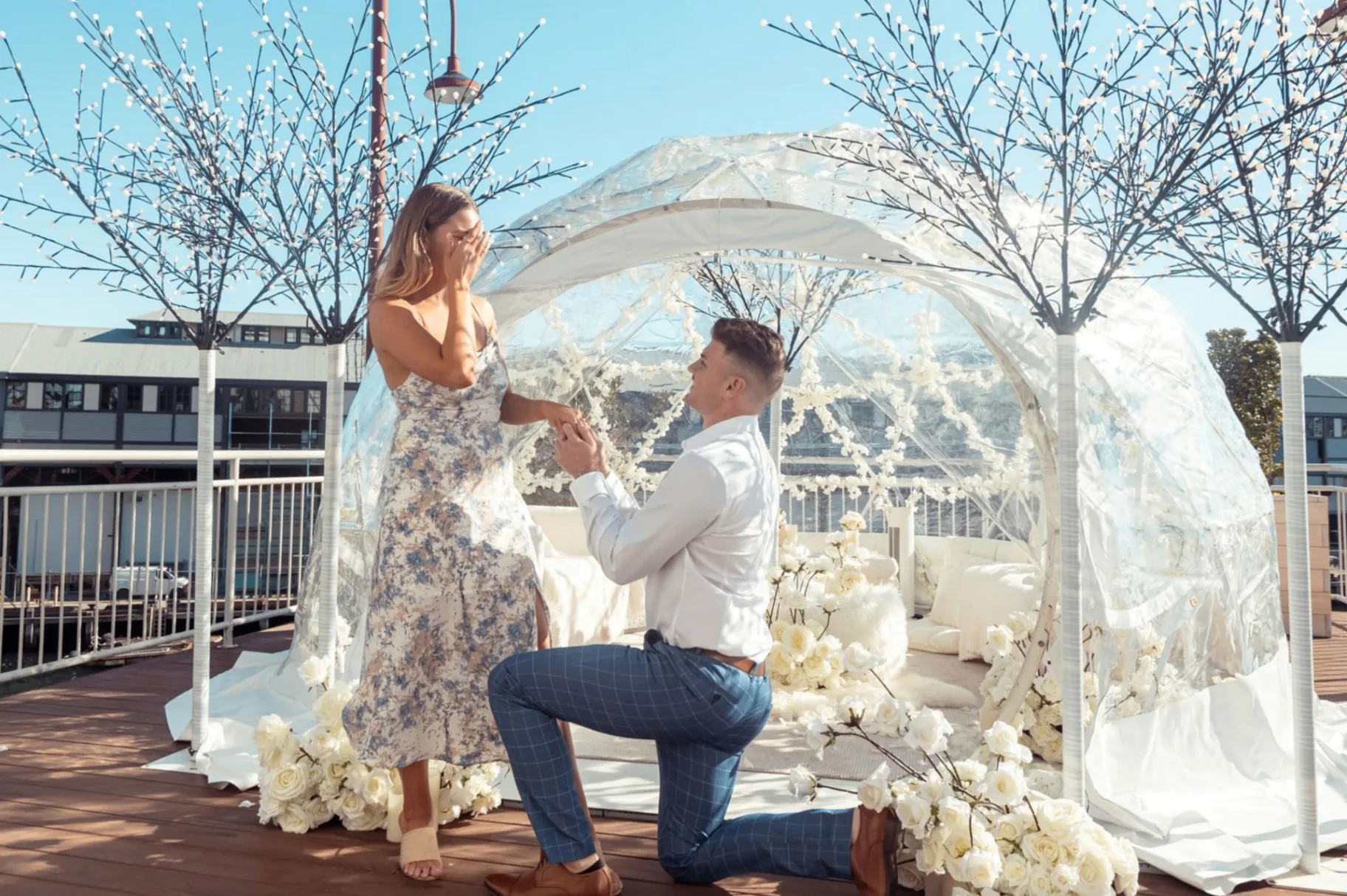 A couple celebrating their proposal beside a candlelit floral arrangement