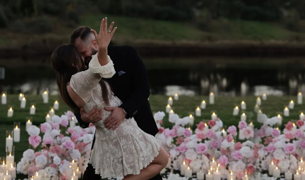 A couple embracing after a candlelit marriage proposal